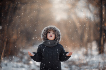 Winter photography with a baby.
A little boy catches snow with his hands.
Child in the snow.