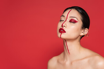 portrait of asian woman with closed eyes and artistic makeup isolated on red.