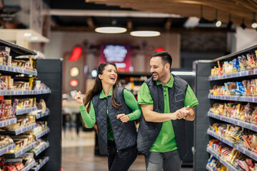 Joyful supermarket workers are dancing at marketplace.