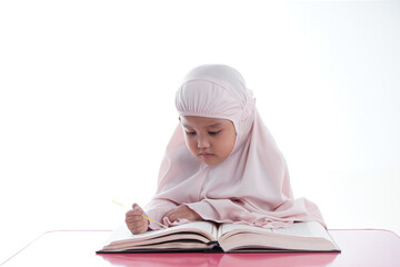 Asian Malaysian Muslim kid is reading the Quran. The Quran is indicated as the guided book for all Muslim and it is direction to be on the heaven of God.Mosque,Islam,religion and knowledge concept.