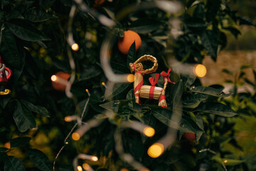 New Year's authentic toy hanging on a tree in an orange garden, around the New Year's lights of garlands - 552102259