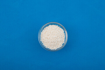 Potassium sorbate, potassium salt of sorbic acid in glass bowl on blue background, top view. Food...