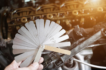 auto mechanic Using Feeler gauge Set the car valve. Measuring valve clearance with tappet feeler gauge set
