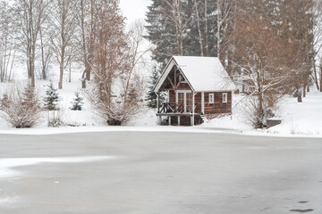 Fototapeta na wymiar Winter landscape with snow covered house,trees and frozen lake