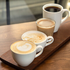 Different types of coffee in cups on a wooden background, cappuccino, americano, latte macchiato