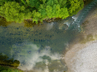 Aerial view of tranquil river flowing through green forest.