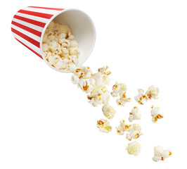 Tasty popcorn falling out of a red striped carton bucket, isolated on white background