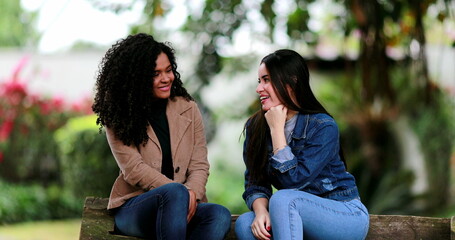 Two young women talking in conversation outside at park