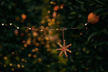 New Year's authentic handmade toy hanging on a tree in an orange garden, around the New Year's lights of garlands - 552109271