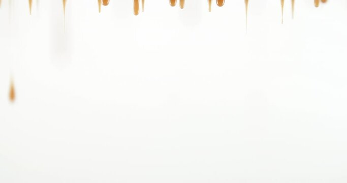 Seamless dripping caramel droplets flowing down liquid sweet sauce on white background. Trickle stream yellow orange tasty syrup drip and flow. Confectionery, cooking dessert and candies. Food concept