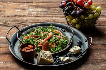 Delicious gourmet cheese, assortment of soft cheeses served with sliced sweet fresh figs and grapes on a rustic wooden background, catering, banner, menu, recipe, place for text