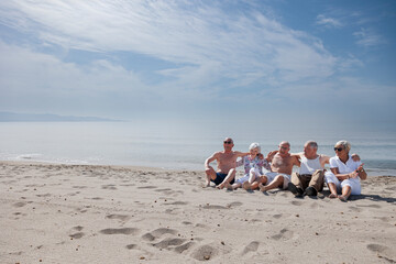 Un gruppo di anziani si diverte seduti nella spiaggia in riva al mare  