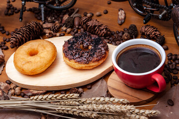 Pączki z dziurką (donaty) na drewnianej desce do krojenia i czarna kawa w filiżance