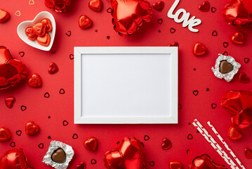 Valentine's Day concept. Top view photo of photo frame heart shaped balloons saucer with chocolate candies straws inscription love and confetti on isolated red background with blank space