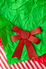 Very beautiful shiny red bow lying on gift paper, concept of gift wrapping and Christmas and New Year celebration.