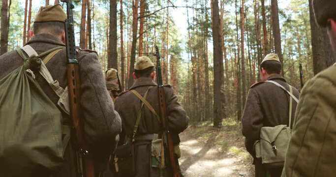 4K Squad Men Dressed As World War II Russian Soviet Red Army Soldiers Marching Through Spring Forest In Sunny day. Soldier Of WWII WW2 Times