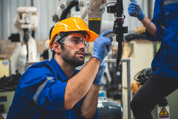 Engineers mechanic using computer controller Robotic arm for welding steel in steel factory workshop. Industry robot programming software for automated manufacturing technology