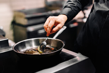Obraz na płótnie Canvas man chef cooking tasty shrimp in frying pan on kitchen 
