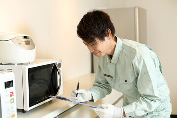 電子レンジを確認する作業員の男性