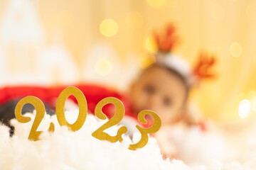Numbers 2023 year on the background of a happy boy in santa hat and deer horns on head with, happy...