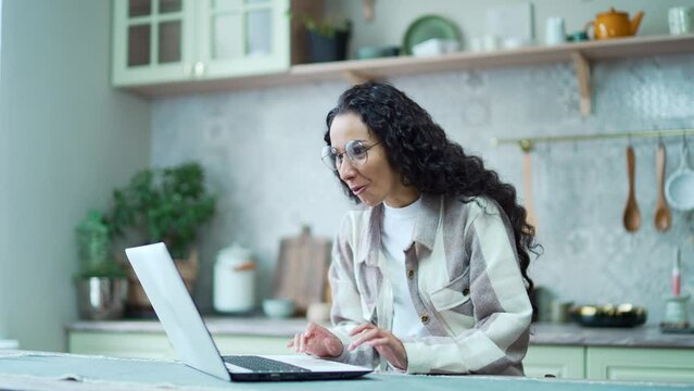 Amazed woman with glasses extremely happy after read email letter on laptop at home Excited brunette looking at computer screen and pleased rejoices received great successful news or result indoors