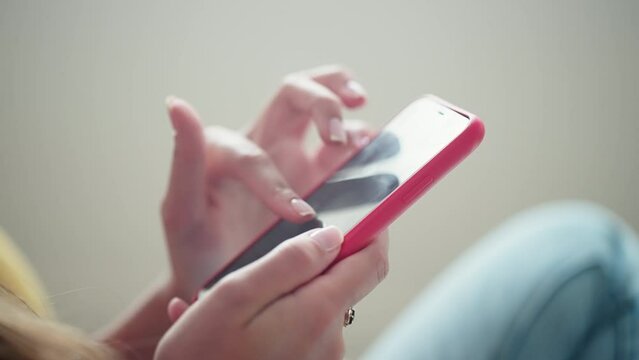 closeup of hands of female internet user with modern smartphone indoors, scrolling and swiping