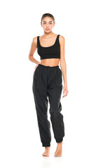 a young barefeet woman in black sweatpants and a tank top on a white background