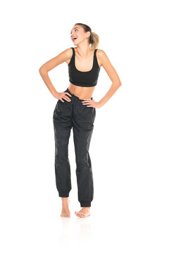 a young barefeet happy woman in black sweatpants and a tank top on a white background