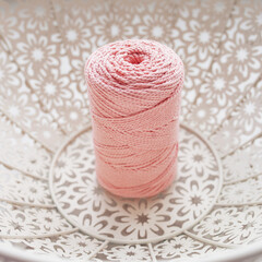 Handmade macrame braiding and cotton threads in white basket. Cotton macrame cords and ropes against wire basket. Good image for macrame and handicrafts banners and advertisement. Close up