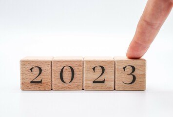 Hand choosing the number 2023 in wooden block cubes isolated on a white background. new year concept