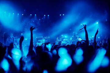Fototapeta na wymiar Under blue spotlights illuminating the smoke, the lights reveal a crowd dancing energetically. An intense blue musical atmosphere perfect to illustrate a rock scene.