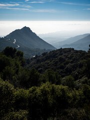 imagen de un valle de monta&ntilde;as con niebla y nubes entre las monta&ntilde;as y el cielo azul