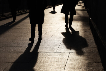 Silhouettes and shadows of people on the street. Legs on sidewalk, concept of crime, society or...