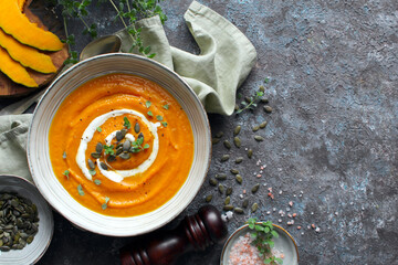 Pumpkin and carrot soup served with cream and seeds. Top view with copy space. Healthy food.