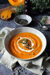 Pumpkin and carrot soup served with cream and seeds. Top view with copy space. Healthy food.