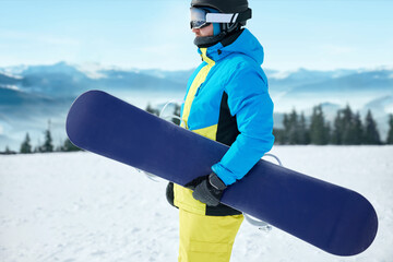 Portrait Of Snowboarder In The Ski Resort On The Background Of Mountains And Blue Sky Wearing Ski...