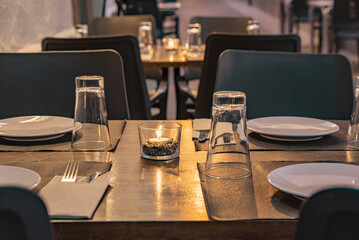 A table prepared with a lit candle on the terrace of a restaurant