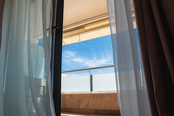 View of the blue sky through the open balcony door