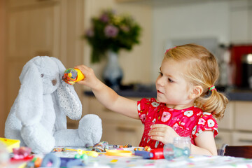 Adorable cute little toddler girl with colorful clay. Healthy baby playing and creating toys from...