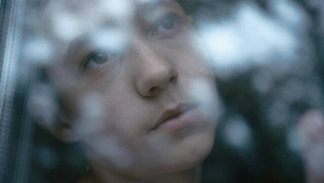 sad alone boy sitting at the window and looking out, difficult life experiences in early childhood, lonely depressed boy near the window, steadicam shot