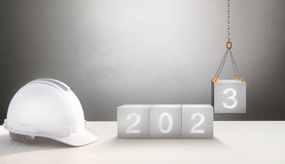 Happy New Year 2023 Construction and Industry. White Helmet and a numbered concrete cube on the...