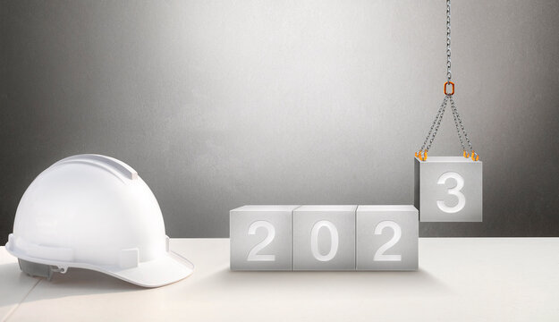 Happy New Year 2023 Construction and Industry. White Helmet and a numbered concrete cube on the desk of an engineer or construction worker. building with Cranes construction concept.	
