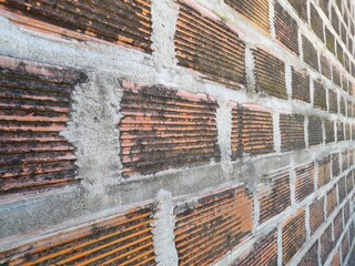 Antiguo muro de ladrillo hueco de cerámica roja con moho negro en la fachada de la casa, alineados en perspectiva, forma un diseño de construcción original para los fondos