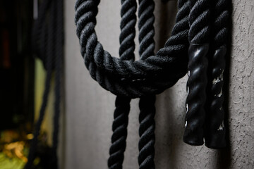 Close up of black battle rope on a gray backgound. Sport and fitness equipment. Functional training.