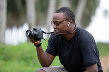 Happy male African photographer with a digital camera in a village in Africa