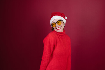Fototapeta na wymiar Young positive woman in christmas santa hat isolated over redl background. Happy young woman in Santa's helper hat a red background.