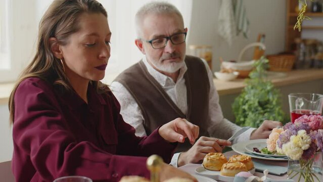 PAN shot of large Caucasian family sharing food while eating festive dinner on Easter day at home