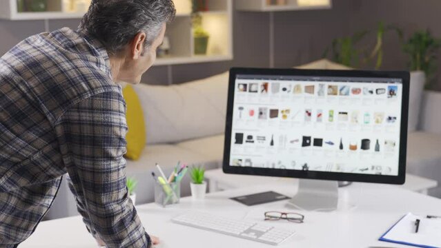 Man is shopping at online internet stores from his computer at home.
A man browsing and researching online shopping sites to buy new products.
