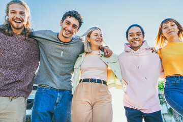 Multiracial group of friends having fun together outdoors on city street- Young cheerful people walking hugging outside- Next gen z lifestyle concept-Smiling student enjoying vacation-Bright filter 