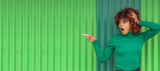 girl pointing surprised on green background outdoors